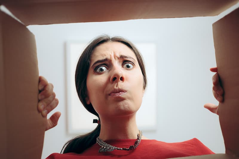 Woman looking in box confused.