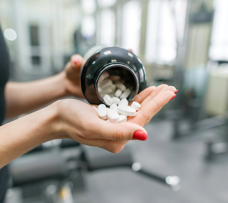 woman pouring supplements in hand packaging